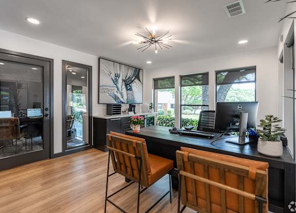 A modern home office with a desk, chairs, and a computer.