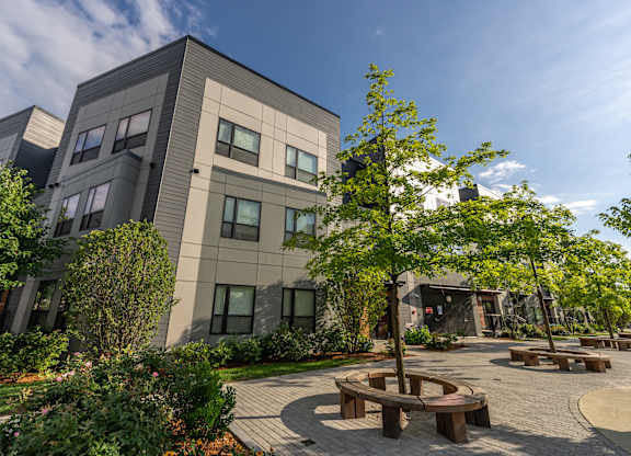 a courtyard with benches and trees in front of a building