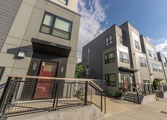 a group of new apartment buildings with stairs and a sidewalk