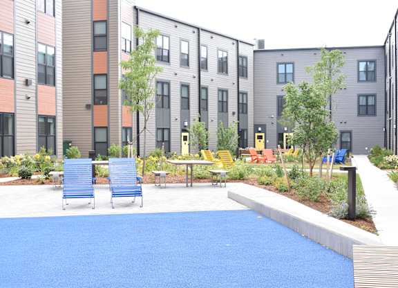 a blue court yard with chairs and tables in front of buildings