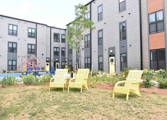a group of yellow chairs in front of an apartment building