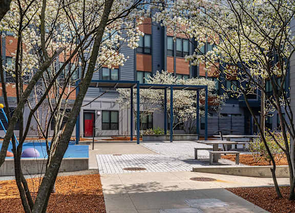 A modern building with a red door and a pool in the courtyard.