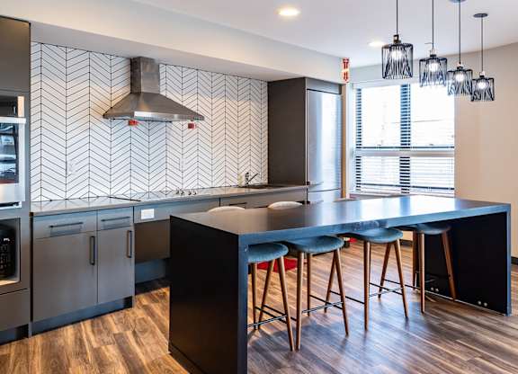A kitchen with a black counter top and bar stools.