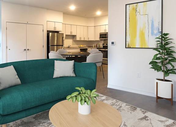 A living room with a green couch, a table with a plant on it, and a painting on the wall.