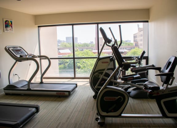 a gym with cardio equipment and a large window