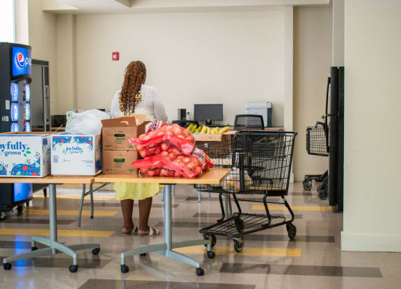 a woman in a white shirt and yellow skirt stands behind a table full of boxes and bags