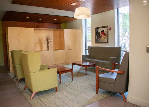 a seating area with chairs and tables in front of a wall with a painting on it