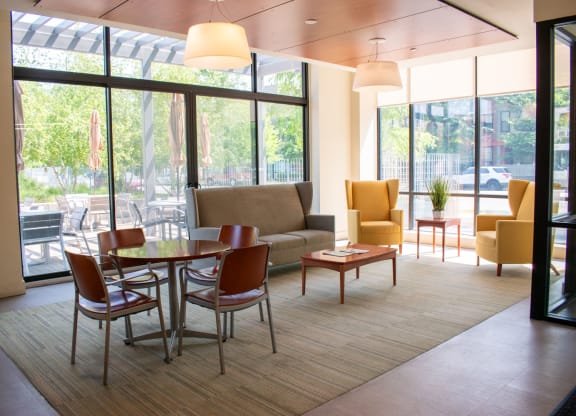a room with a couch table and chairs and large windows