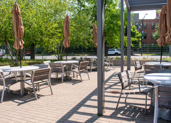 a patio with tables chairs and umbrellas on a sunny day