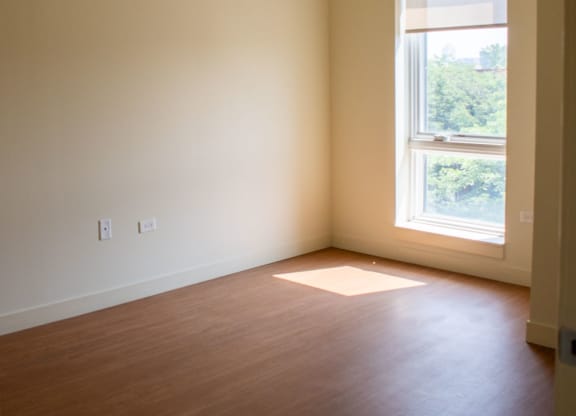 an empty room with a window and wooden floors