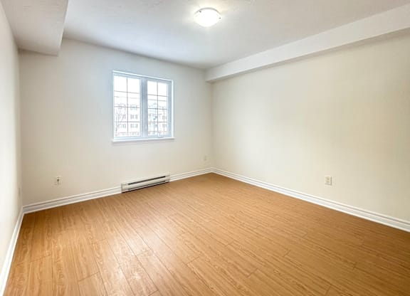 A room with a window and a wooden floor.