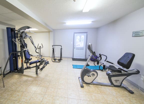 A gym room with a treadmill, weights, and a bench press.