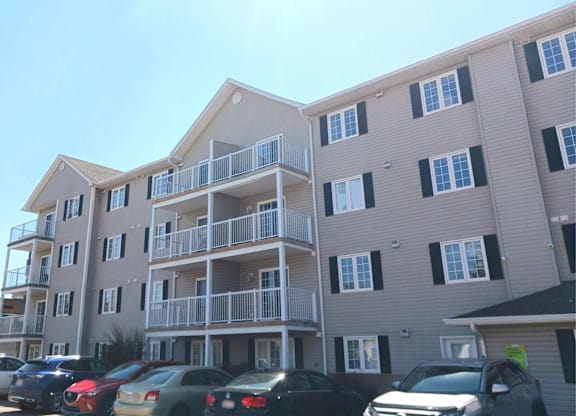 A sunny day at a residential building with cars parked in front.