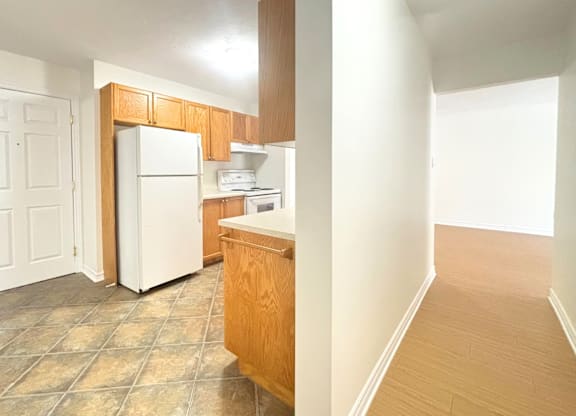 A kitchen with a refrigerator, sink, and cabinets.