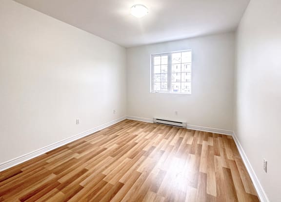 A room with wooden flooring and a window.