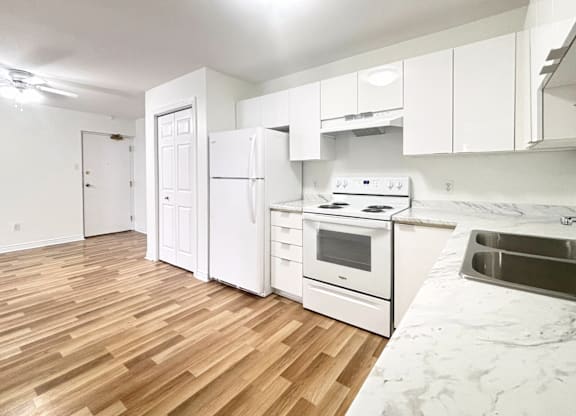 A kitchen with white appliances and wooden floors.