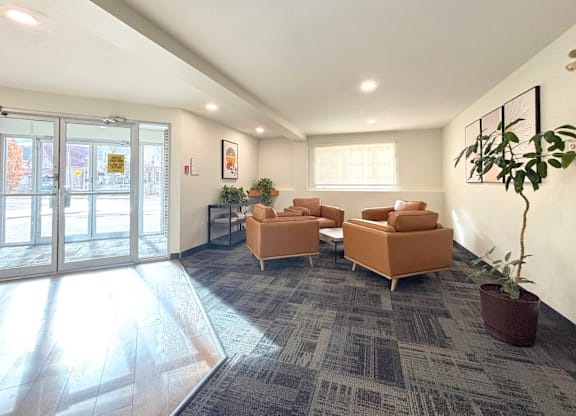 A spacious waiting room with a grey carpet and orange chairs.