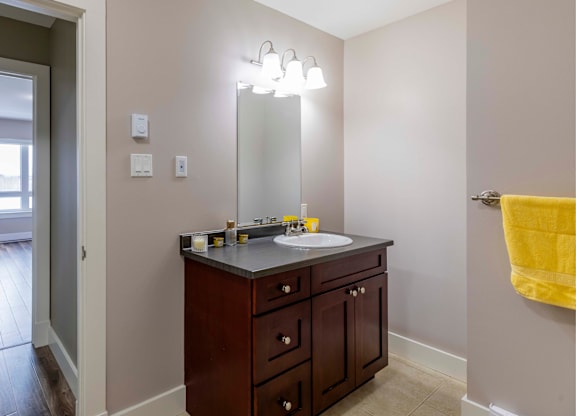A bathroom with a sink, mirror, and lighting fixture.