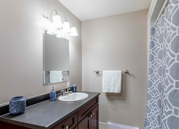 A bathroom with a sink, mirror, and towel rack.