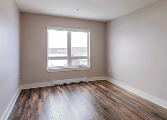 A room with a large window and wooden flooring.