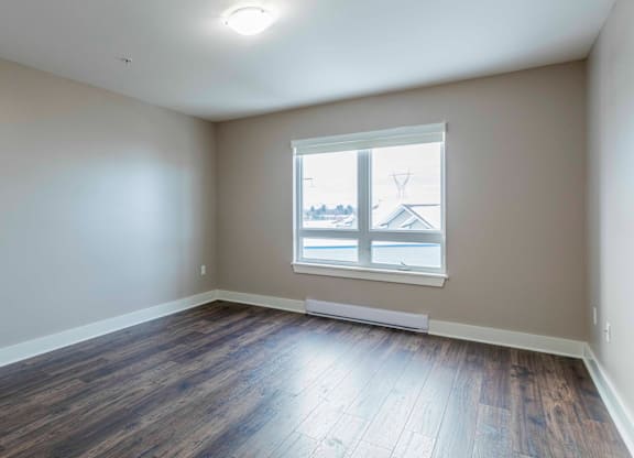 A room with a window and wooden flooring.
