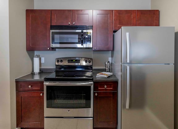 A kitchen with a stainless steel refrigerator, oven, and microwave.