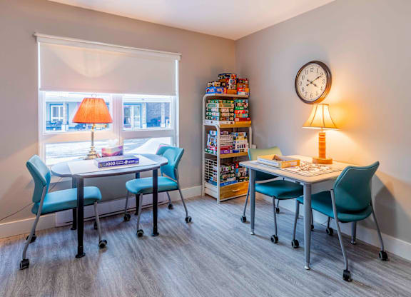 A room with a desk, chairs, and a clock on the wall.