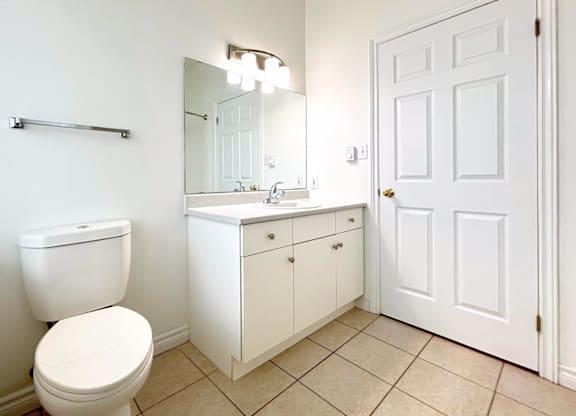 A white bathroom with a toilet, sink, and mirror.