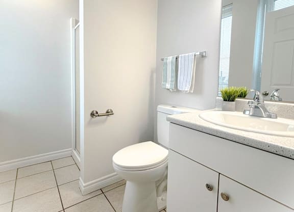 A white bathroom with a toilet, sink, and mirror.