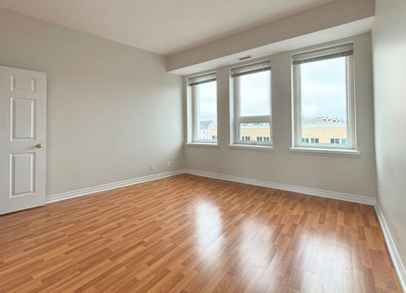 A room with wooden floors and three windows.