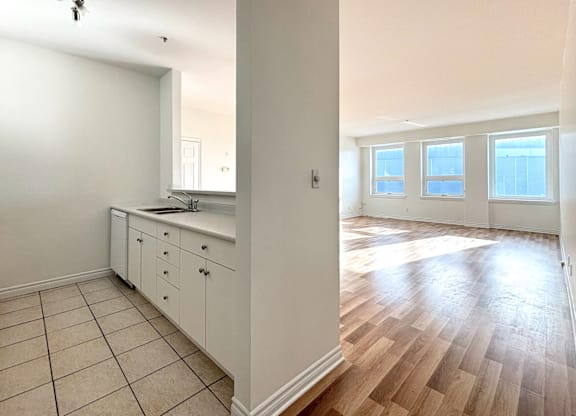 A kitchen with white cabinets and a wooden floor.