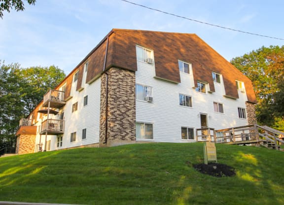 A white house with a brown roof and a stone chimney.