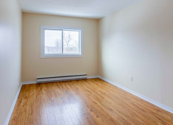 Empty room with a window and wooden floor.