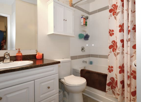 A white toilet sits in a bathroom with a brown towel on the tub.