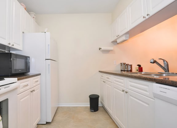 A kitchen with white cabinets and appliances.
