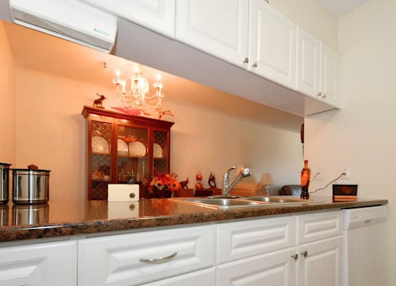 A kitchen with white cabinets and a marble countertop.