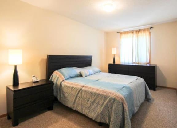 A bedroom with a bed, nightstand, and lamp.