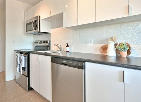 A modern kitchen with white cabinets and stainless steel appliances.