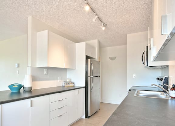 A kitchen with white cabinets and a stainless steel refrigerator.