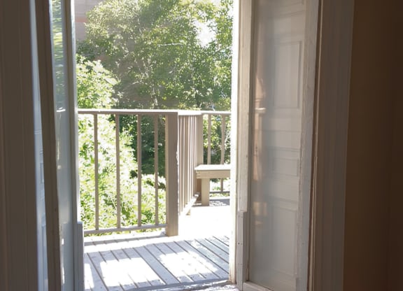 A white door opens to a balcony with a table and chairs.