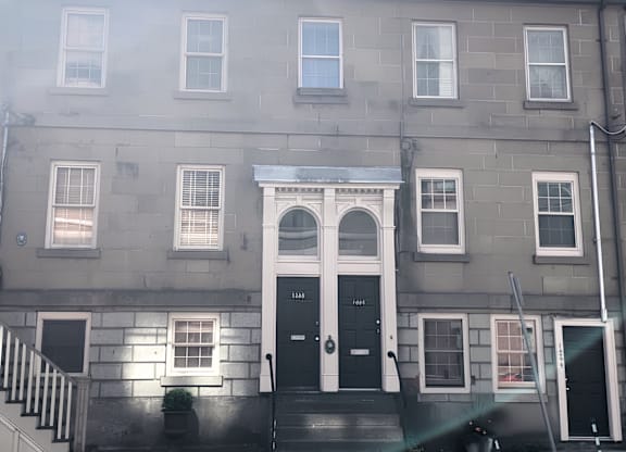 A grey building with a black door and windows.