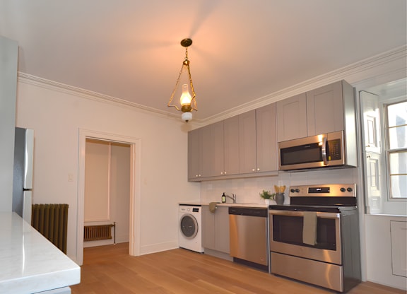 A kitchen with a white counter top and stainless steel appliances.