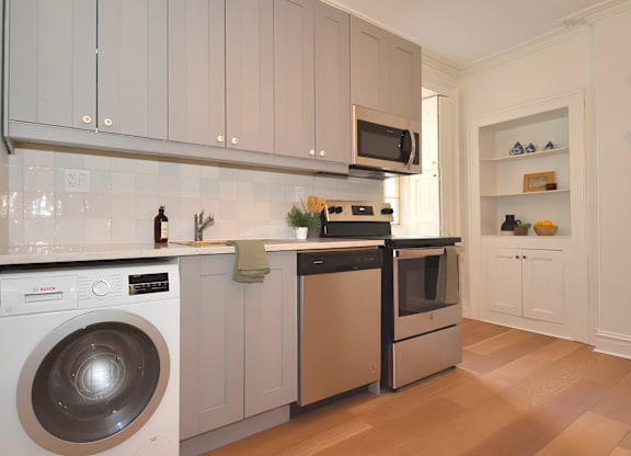 A modern kitchen with a washing machine and a microwave.