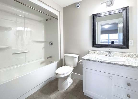 A white bathroom with a toilet, sink, and shower.