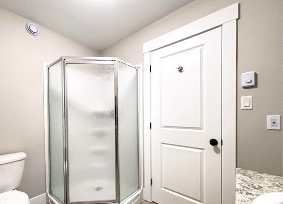 A white door is open to a bathroom with a walk-in shower.