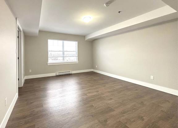A room with a window and wooden flooring.