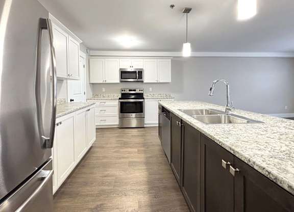 A modern kitchen with a stainless steel refrigerator and a marble countertop.