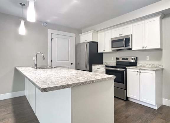 A kitchen with a granite countertop and stainless steel appliances.