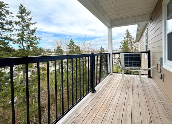 A balcony with a black railing and a wooden floor.