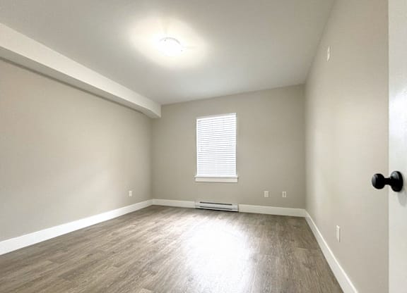 A room with a window and a wooden floor.